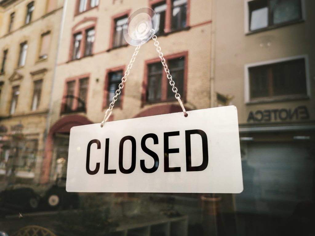 Closed sign inside business door to represent closings due to COVID-19